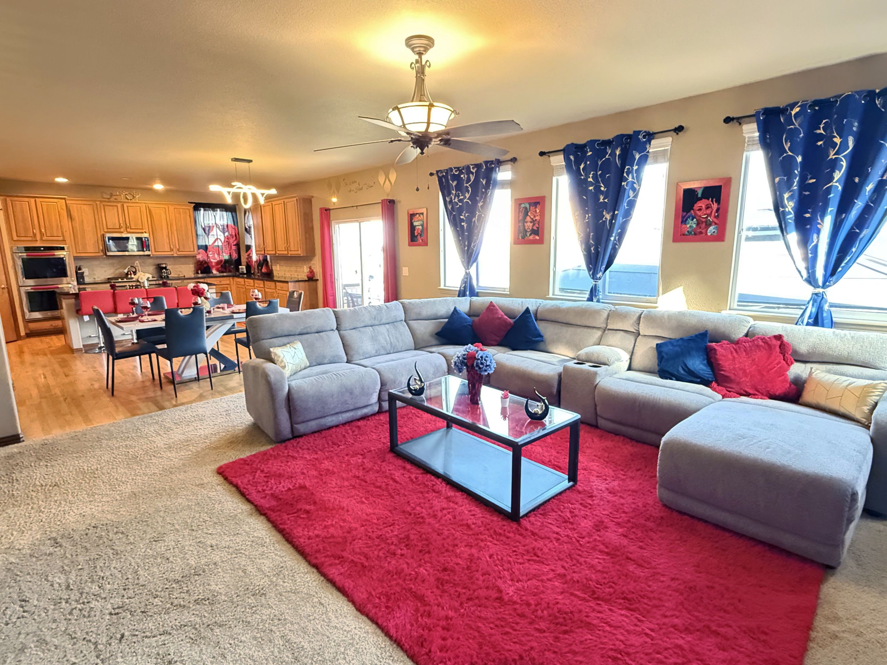 A modern living room with a sectional sofa, a glass coffee table, and a red rug.