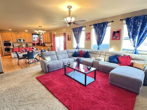 A modern living room with a sectional sofa, a glass coffee table, and a red rug. - GolfSim HotTub PS5 Sauna Thtr Pooltbl 6BR 5BA 420 (Thornton, CO, 80602)