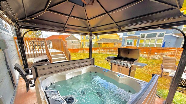 A hot tub with a covered patio, a grill, and a wooden deck with stairs. - GolfSim HotTub PS5 Sauna Thtr Pooltbl 6BR 5BA 420 (Thornton, CO, 80602)