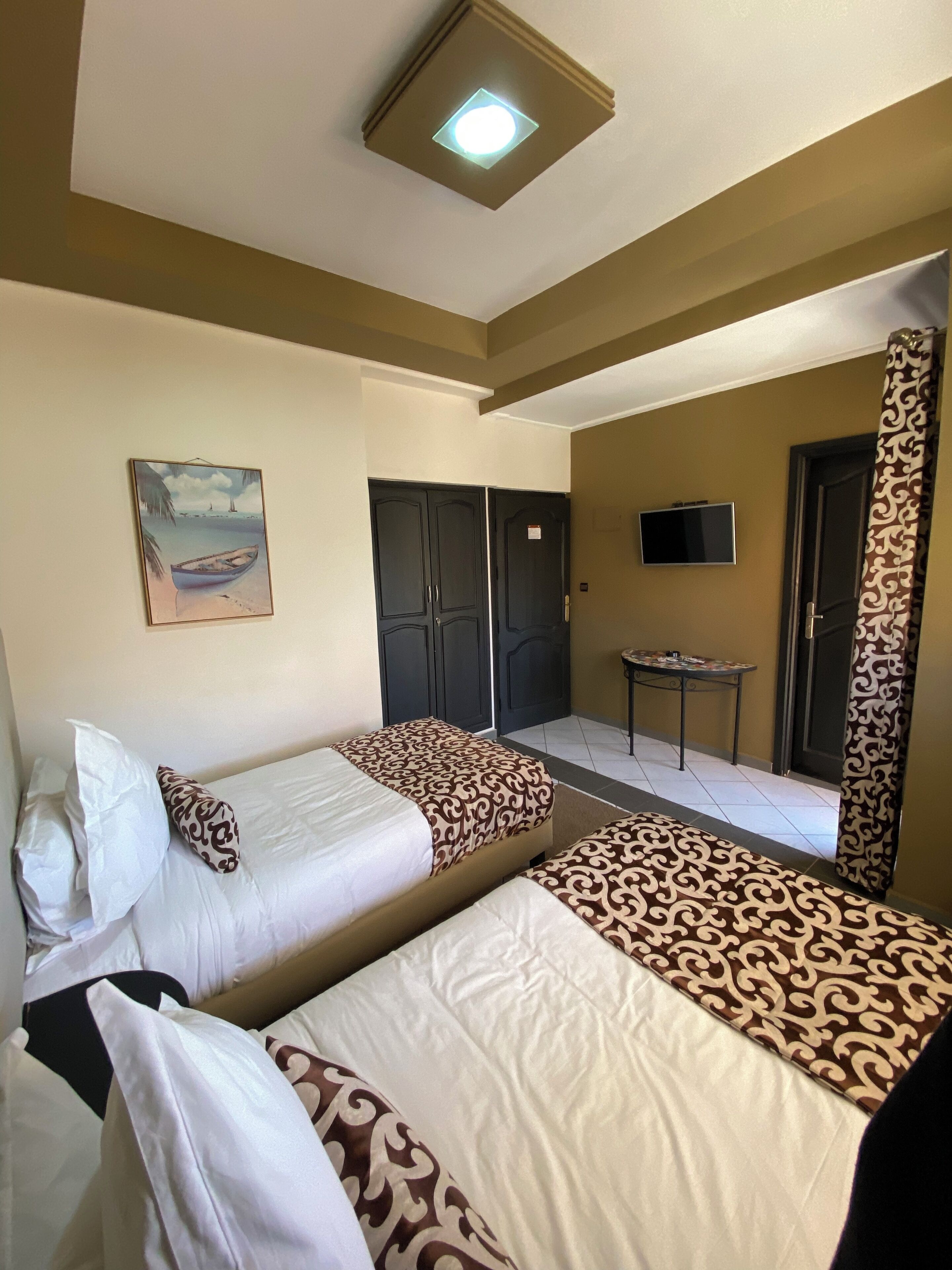 A hotel room with two beds, a painting, a TV, and a small table.