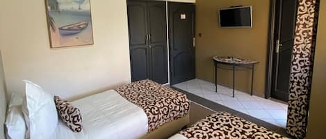 A hotel room with two beds, a painting, a TV, and a small table.