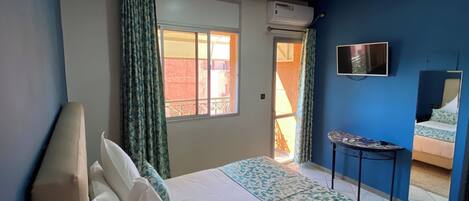 A bedroom with a bed, a TV, and a small table.