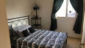 A bedroom with a bed, a nightstand, a window with curtains, and a door. - Lovely 4-bed Villa in L'ametlla de Mar, off Grid , (L'Ametlla de Mar)
