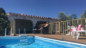 A pool area with a clear blue pool, a wooden deck, and a building with a tiled roof in the background. - Lovely 4-bed Villa in L'ametlla de Mar, off Grid , (L'Ametlla de Mar)