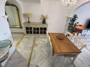 A dining area with a wooden table and white chairs, a white cabinet with glass doors, a chandelier, and a large mirror. - Marbella Magna Apartment With Stunning Views (Marbella)