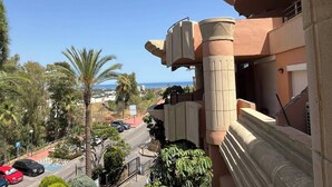 Un hôtel avec vue sur la mer, des palmiers et un espace de stationnement.