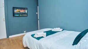 A hotel room with a bed, a TV mounted on the wall, and a folded towel on the bed.