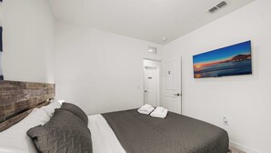 A hotel room with a bed, a painting, a private door, and a view of the sea.