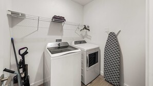 A laundry room with a washing machine, dryer, and ironing board.