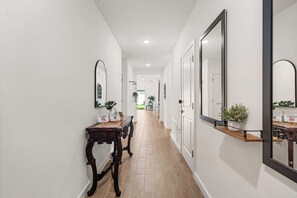 A hallway with a wooden table, a mirror, and a door.
