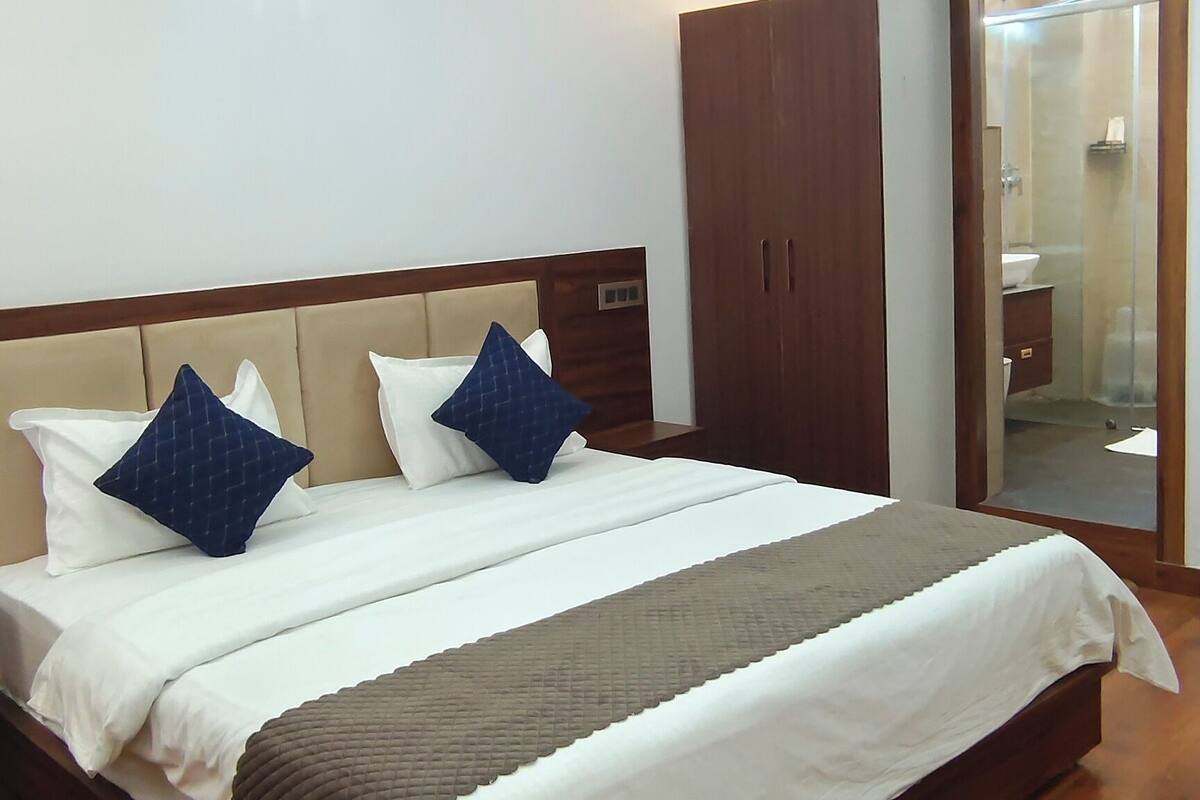 Une chambre à coucher avec un lit, une tête de lit en bois, un ventilateur de plafond et une armoire en bois.