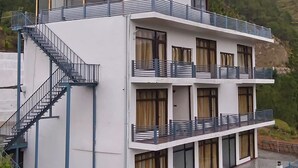 Ein mehrstöckiges Gebäude mit Treppe, Balkonen und Blick auf eine Hügelkette.