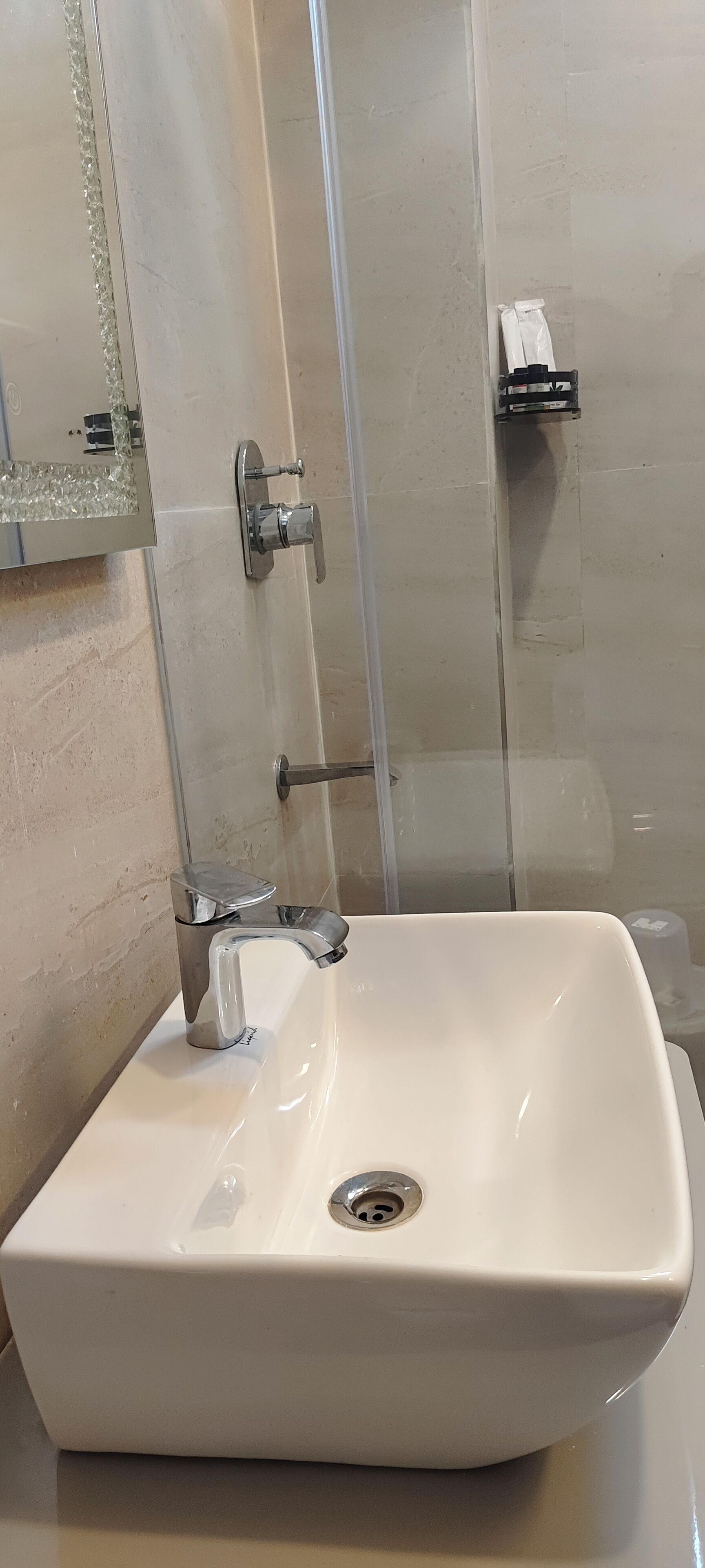 A bathroom with a white sink, a glass shower enclosure, and a tiled wall.