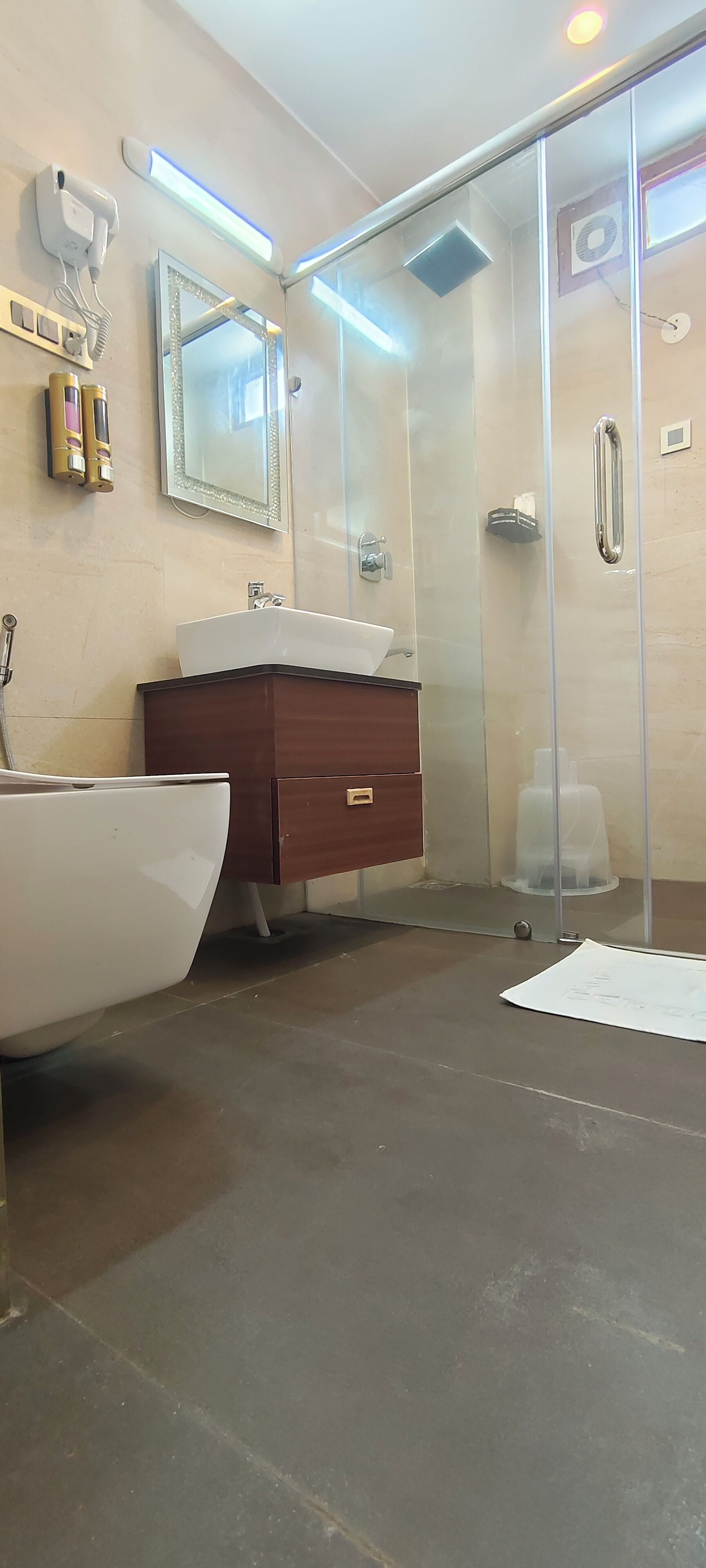 Une salle de bain moderne avec une douche à l’italienne en verre, un lavabo blanc et un meuble-lavabo en bois.