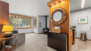 A cozy living room with a fireplace, a large mirror, and a view of the outdoors through the windows.