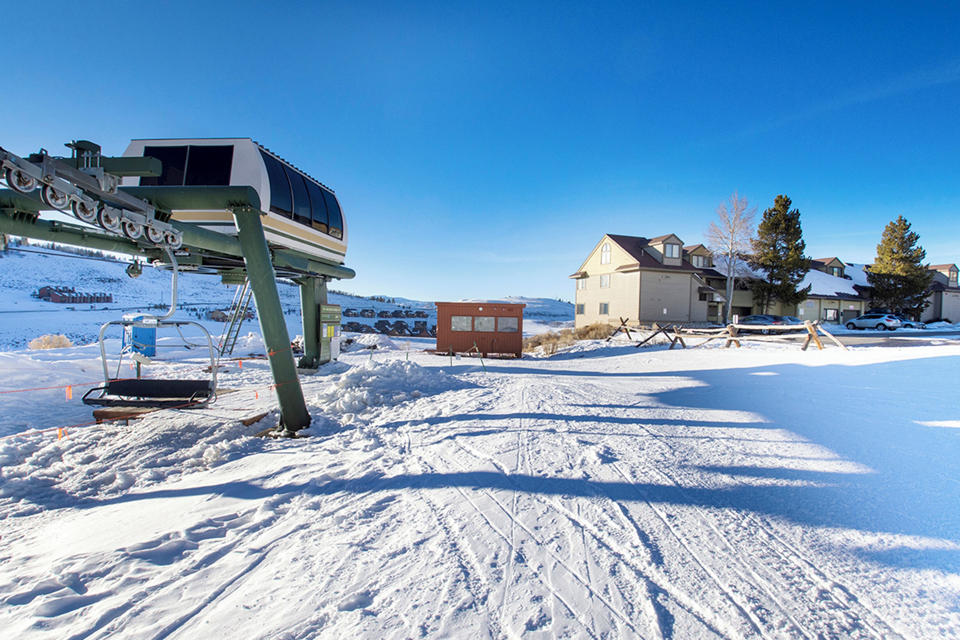 A ski lift, a snow-covered landscape, and a building with a sloped roof.