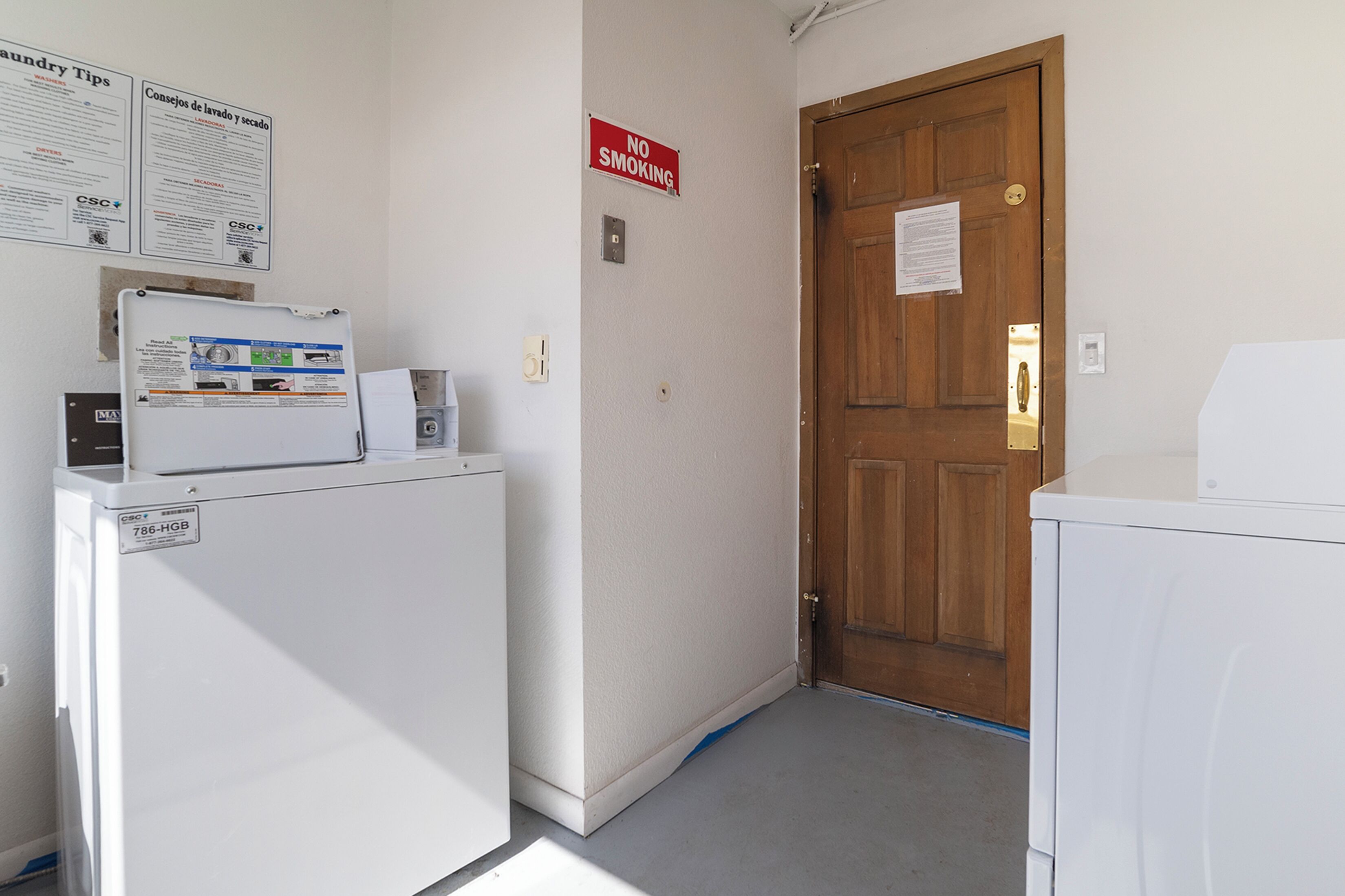 A laundry area with a washing machine, dryer, and a door with a 'No Smoking' sign.
