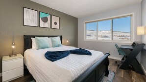 A bedroom with a bed, bedside tables, a desk, and a large window. - Summit Unit 1103 2 bed ground floor, pet friendly condo, ski-in/ski-out access (Granby)