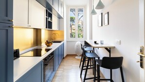 A compact kitchen with modern appliances, a dining area with bar stools, and a window providing natural light. - Charming Home near San Giovanni (Rome)