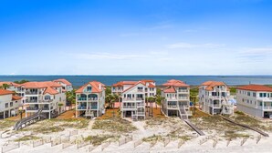Un hôtel en bord de mer composé de plusieurs bâtiments, chacun doté de balcons et offrant une vue directe sur l’océan.