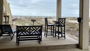 A covered outdoor seating area with wooden furniture and a view of the beach. - Moonlight Sonata - Gulf Front (St. George Island)