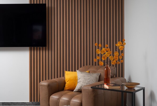 A modern living room with a leather sofa, a glass coffee table, and a decorative vase with yellow flowers.