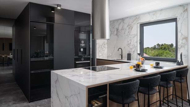 A modern kitchen with a marble countertop, black chairs, and a large window. - Penthouse Adela (Vir)