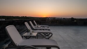 A rooftop terrace with lounge chairs and tables, overlooking a sunset. - Penthouse Adela (Vir)