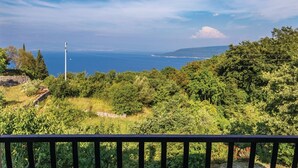 A coastal landscape with dense greenery and a clear view of the sea.