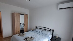 A bedroom with a bed, a wardrobe, a bedside table, and an air conditioning unit.