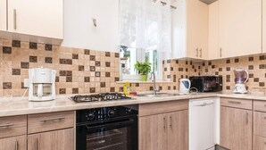 A modern kitchen with a gas stove, coffee maker, microwave, and dishwasher.