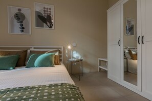 Une chambre bien rangée, avec un lit, des oreillers, une table de chevet avec une lampe et une armoire.
