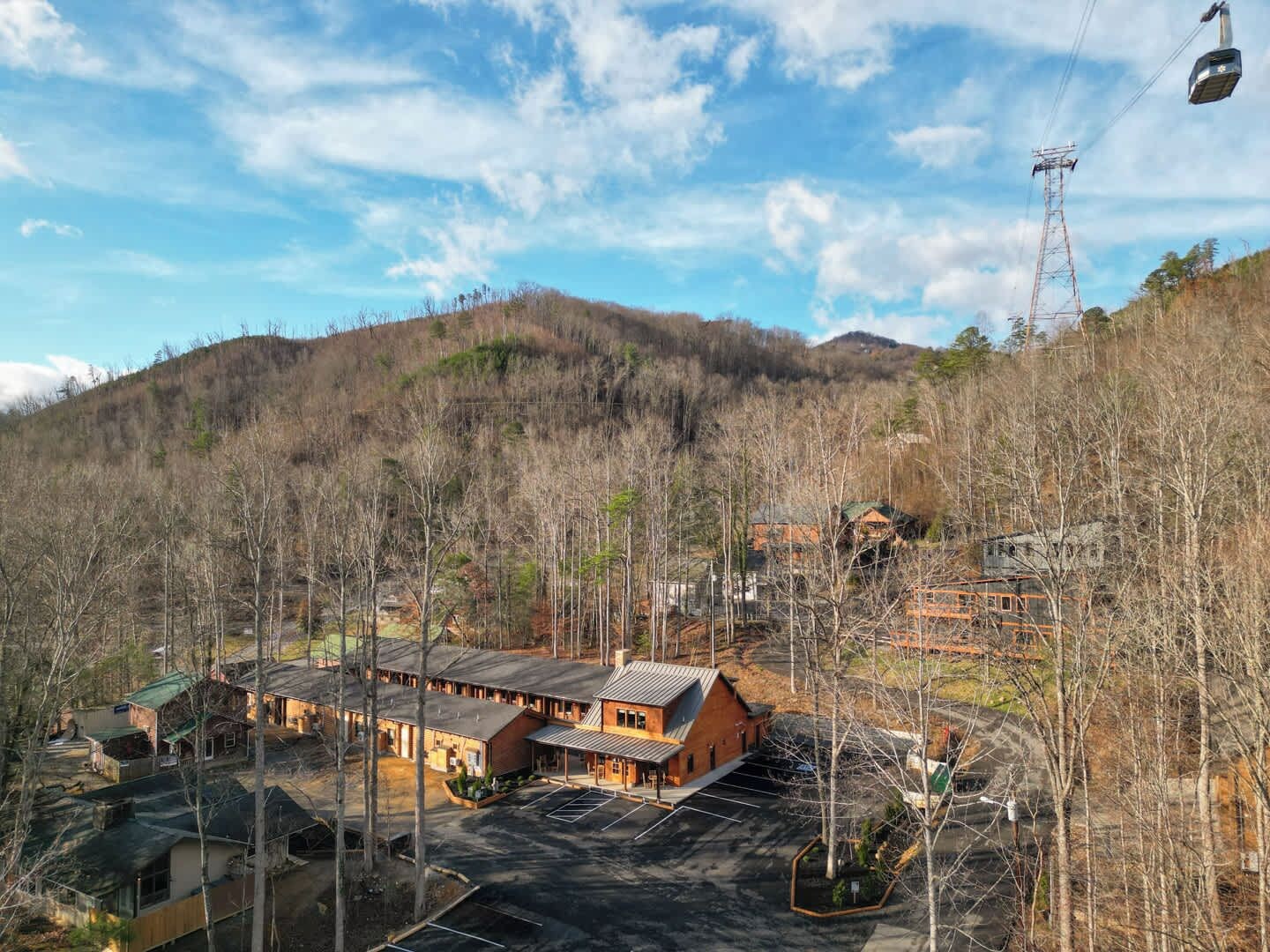 A lodge with a large building, a parking area, and a mountain backdrop.
