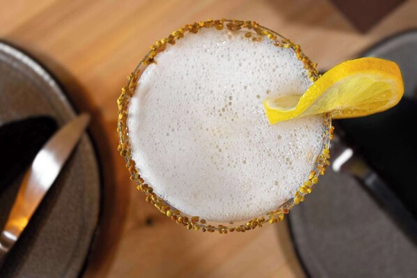 A cocktail in a glass with a gold rim and a lemon garnish.