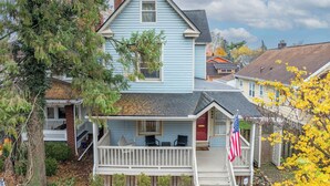 Une maison à deux étages avec un porche, une petite terrasse et un drapeau américain.