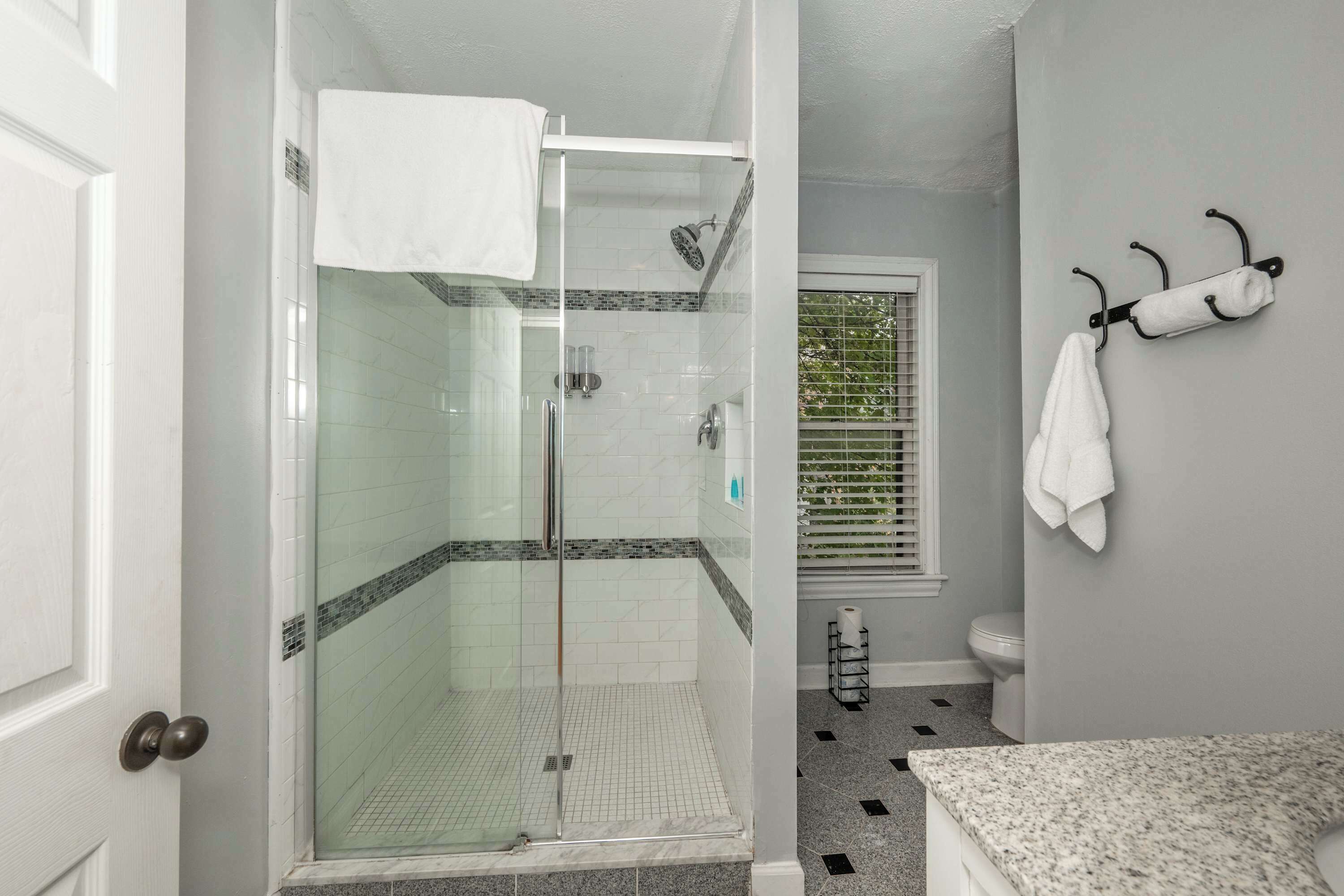 Une salle de bain dotée d’une douche à parois de verre, de toilettes et d’un lavabo avec un plan de travail en granit.