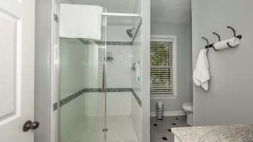 Une salle de bain dotée d’une douche à parois de verre, de toilettes et d’un lavabo avec un plan de travail en granit.