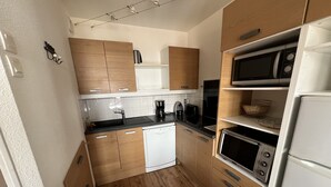 A compact kitchen with wooden cabinets, a dishwasher, a microwave, and a toaster. - VALMEINIER : Beautiful apartment in the heart of Valmeinier 1900, 8 people (Valmeinier)