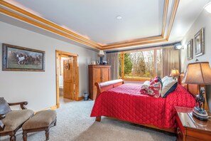 Un dormitorio con una cama grande, muebles de madera, una ventana con cortinas e imagen enmarcada en la pared.