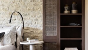 Een moderne kamer met een stenen muur, een donker houten boekenkast, een ronde witte tafel en een grijze bank.