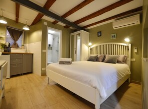 A bedroom with a bed, bedside table, and a bathroom visible through an open door. - Rovinj Old Town Hip and Cozy Studio Apartment (Rovinj)
