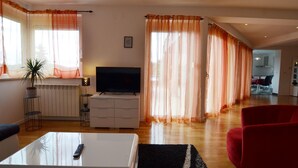 A living room with a TV, a coffee table, a red chair, and a plant. - Calm Countryside Rovinj Manor With Pool (Rovinj)