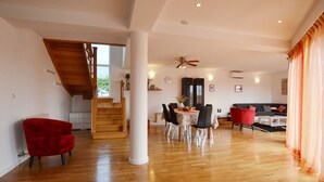 A spacious living area with a wooden staircase, a dining table with chairs, a red armchair, and a sofa. - Calm Countryside Rovinj Manor With Pool (Rovinj)