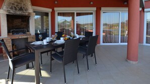 An outdoor dining area with a brick fireplace, a table set for two, and a view of the surrounding landscape. - Calm Countryside Rovinj Manor With Pool (Rovinj)