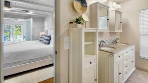A bedroom with a bed, a white vanity with a mirror, and a window with blinds. - Siesta Dreamin’ - Canal Front Home with Private Pool and Dock! (Siesta Key)