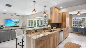 A modern kitchen with a large island, wooden cabinets, and pendant lighting. - Siesta Dreamin’ - Canal Front Home with Private Pool and Dock! (Siesta Key)