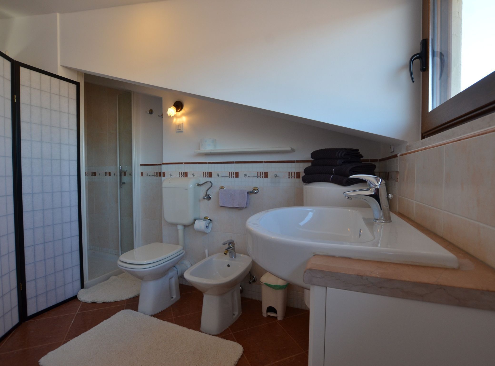 Baño compacto con inodoro, lavabo, ducha y bidé.