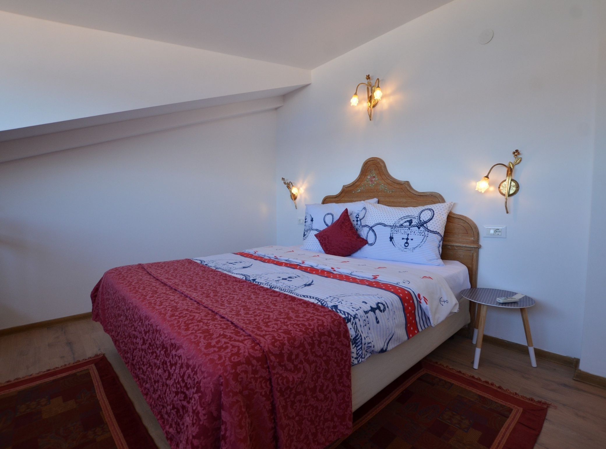 A bedroom with a bed, a nightstand, and wall-mounted lighting.