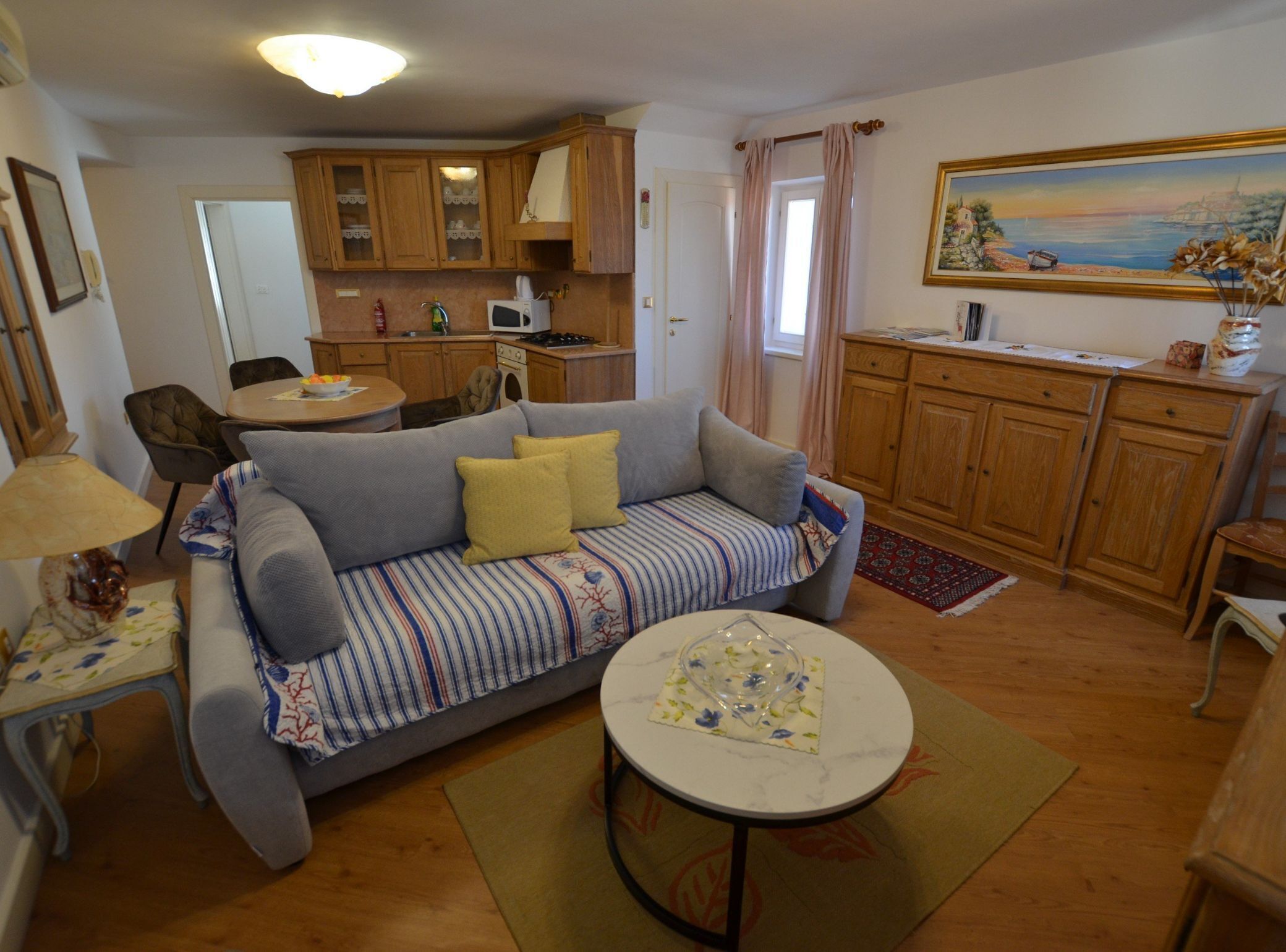 A cozy living room with a sofa, a small round table, and a kitchen in the background.