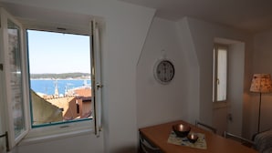 A room with a view of the sea, a dining table with a bowl, a clock, and a lamp. - Blissful Bay Apartment Rovinj Center (Rovinj)